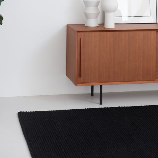 Mini loop tapijt in het zwart gecombineerd met andere meubels in een woonkamer.ALT