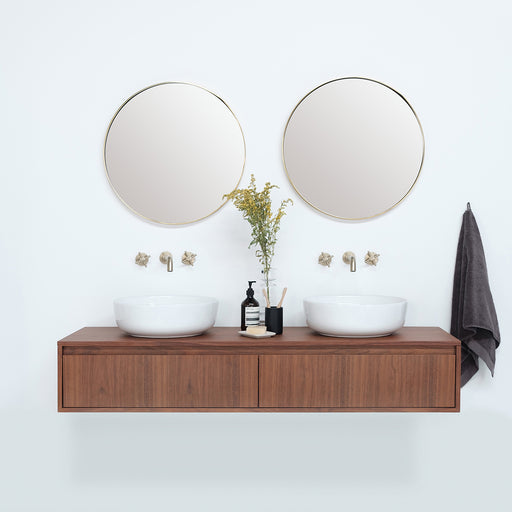 Witte ronde porseleinen waskommen op korte zwevende badkamerkast, gouden kranen, gouden spiegel